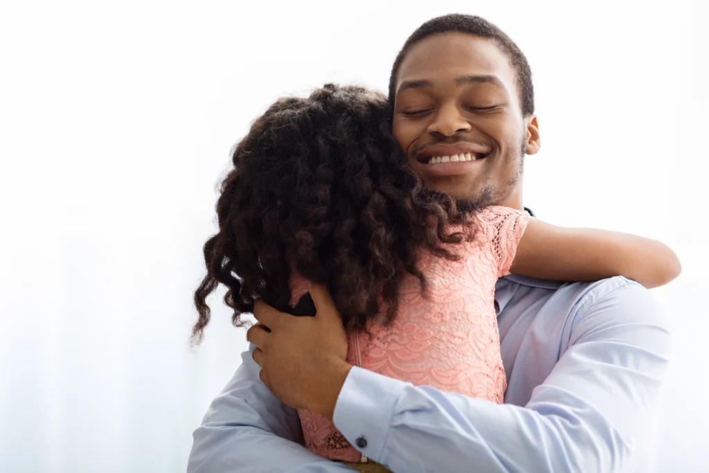 Man in a light blue shirt warmly hugging a young child in a pink dress, representing the strong parent-child bond and fathers’ rights in California child custody cases focused on the best interests of the child.